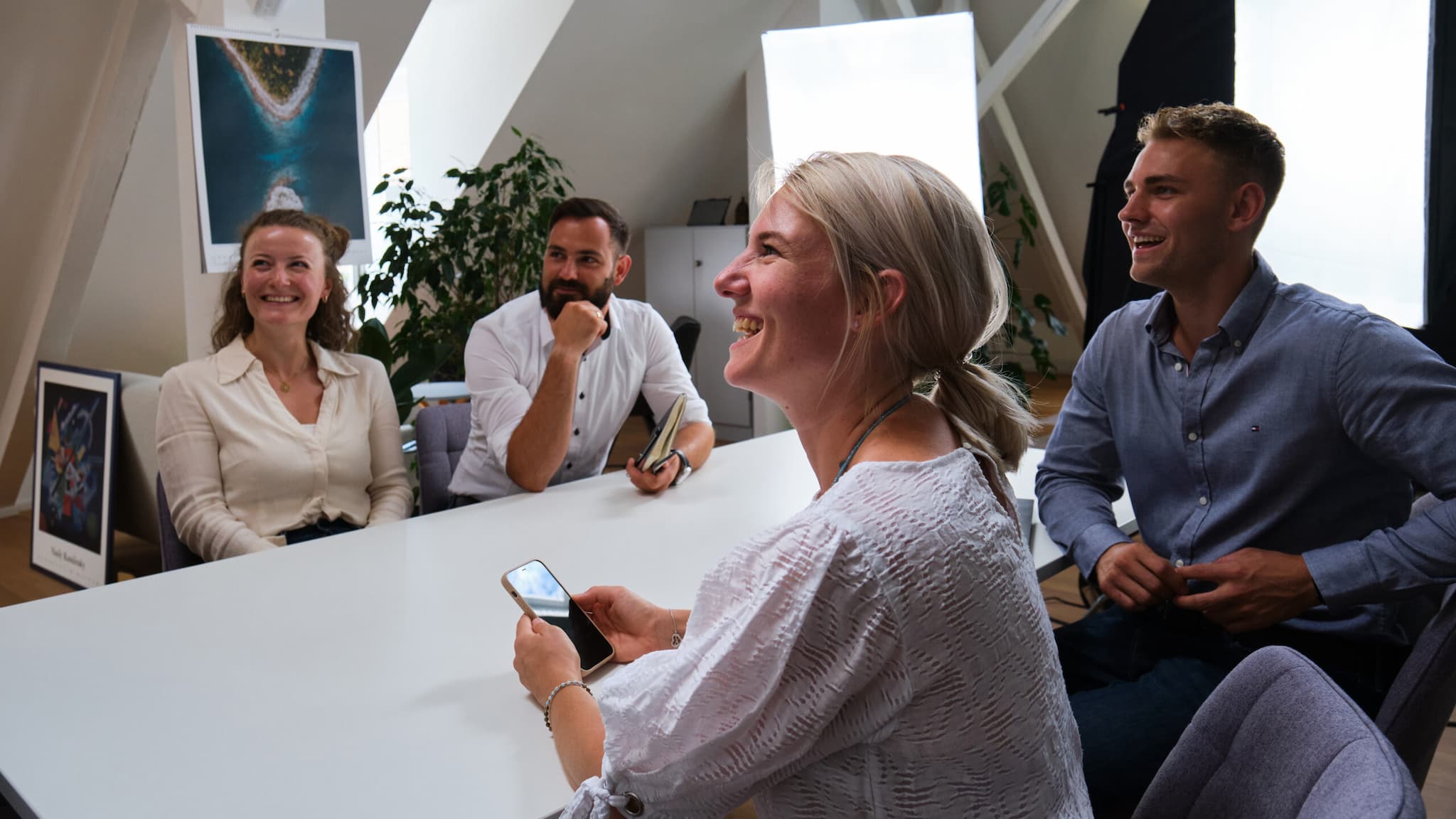 Drei Mitarbeitende von ServiceFactum sitzen am Meetingtisch und schauen lächelnd nach links.