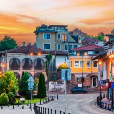 Sonnenuntergang mit einem charmanten bulgarischen Dorf und einer Straße im Vordergrund.