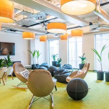 Bürolounge unseres Partners in Polen mit Loungestühlen, Sitzsäcke, Pflanzen und einem Fernseher im Hintergrund.